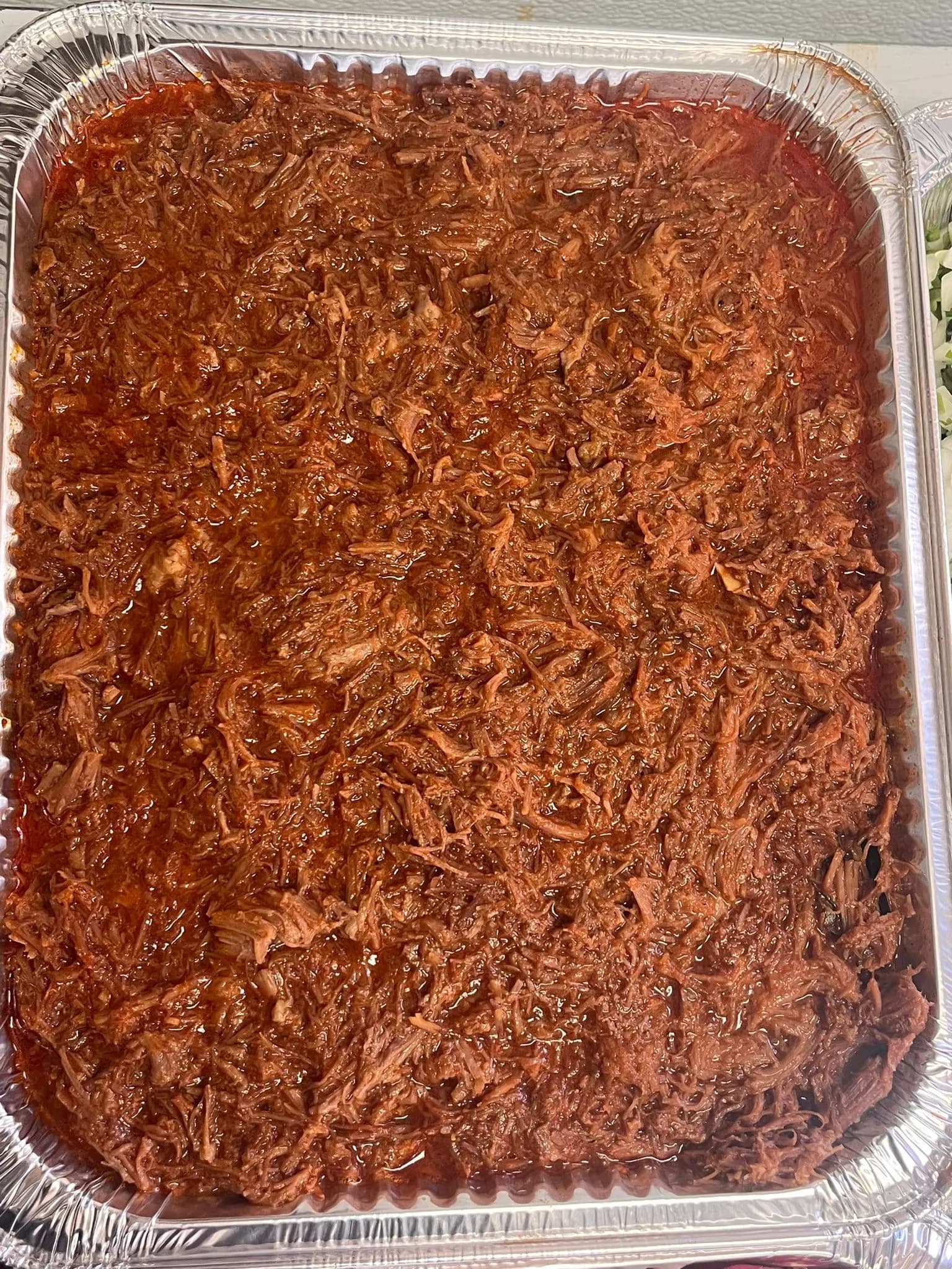 Full tray of slow-cooked shredded birria for catering at Mr. Birria